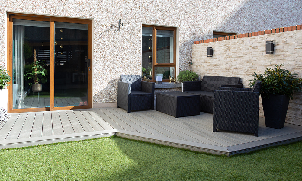 A step-by-step composite decking installation in an Irish garden, showing the hidden clip system being screwed into a pressure-treated timber frame.