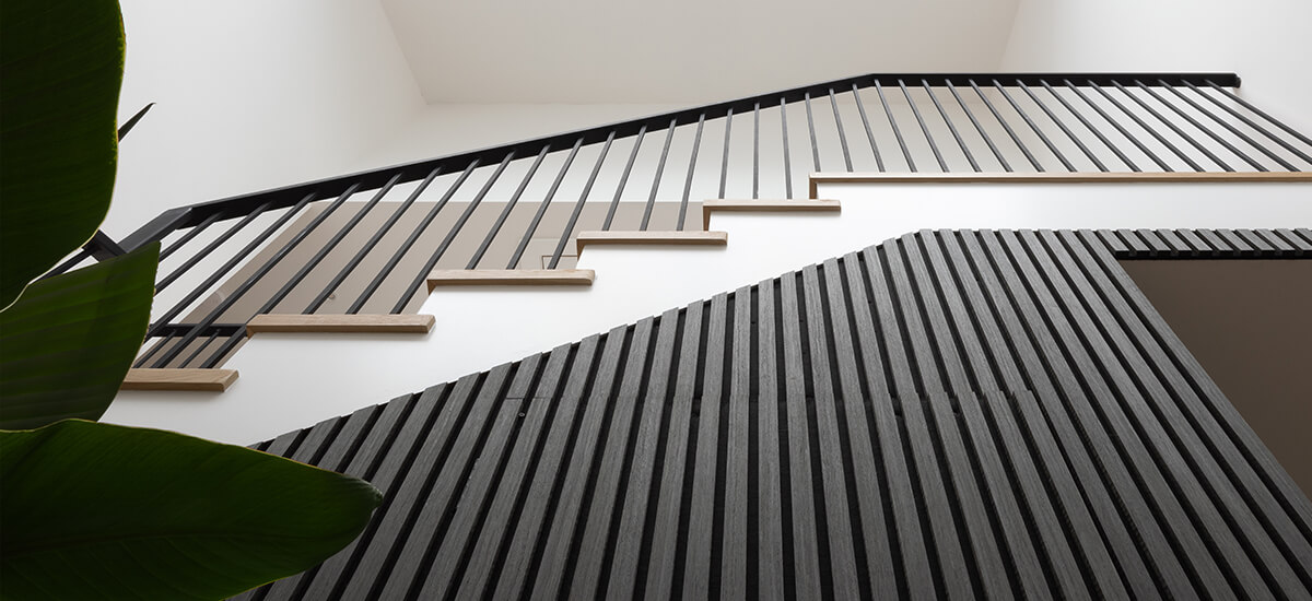 Modern hallway and staircase panelling featuring vertical oak slats and half-height wainscotting, showing a durable and stylish interior design solution for homes.