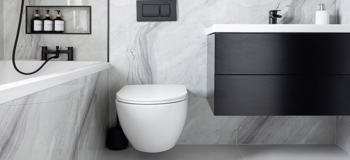 A small modern bathroom featuring large format white glossy wall tiles and light grey matt floor tiles to create a bright, airy space.