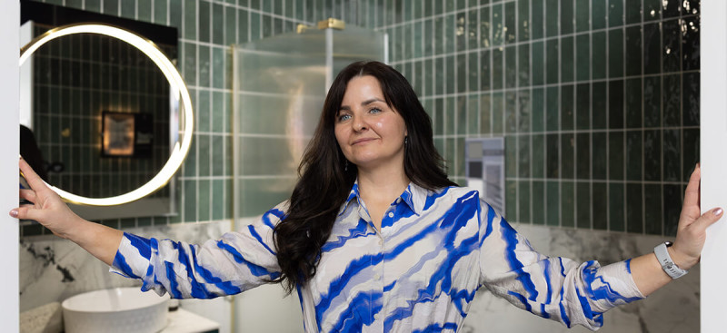 Expert interior designer Wioleta Kelly discussing small bathroom tiles ideas in the Ashbourne showroom, featuring large-format marble-effect and wood-effect porcelain displays.