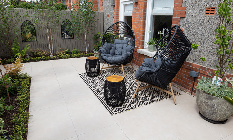 A side-by-side comparison of natural sandstone, limestone, and granite paving slabs next to a modern light grey 20mm outdoor porcelain tile, showcasing the different textures for an Irish garden.
