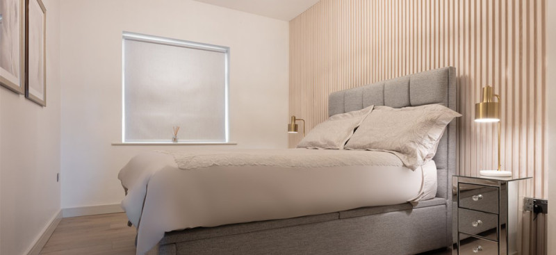 Modern living room featuring floor-to-ceiling vertical wood slat panelling as a decorative feature wall installed in a bedroom.