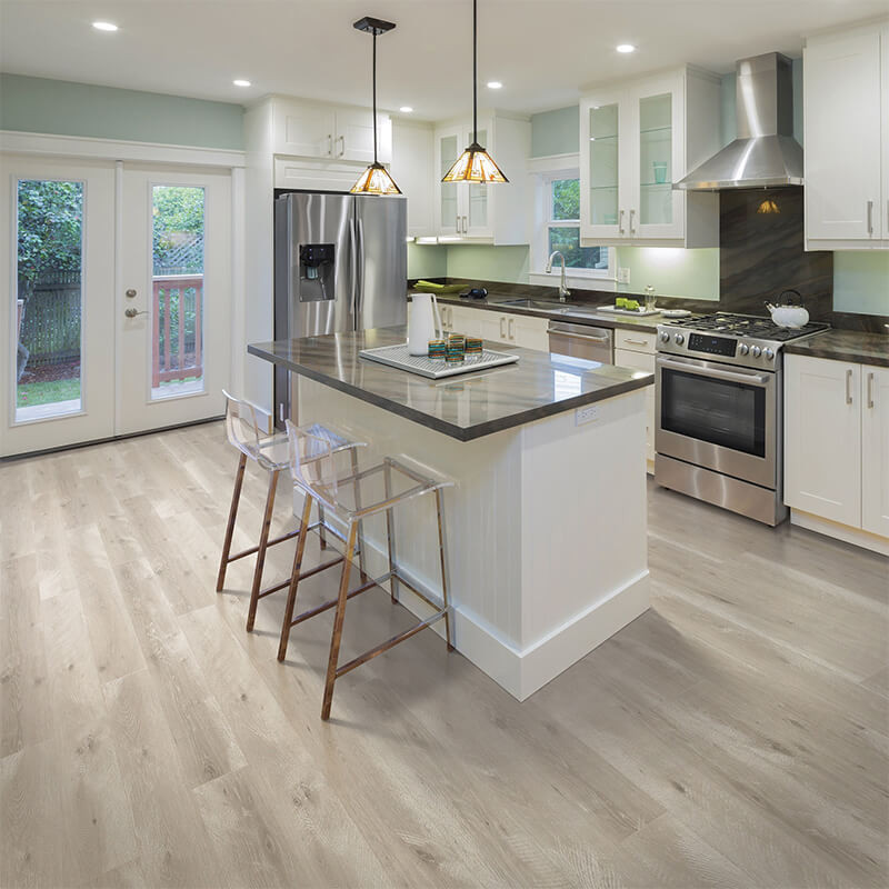 Wide plank laminate flooring in a rich brown tone adds warmth to a modern kitchen.