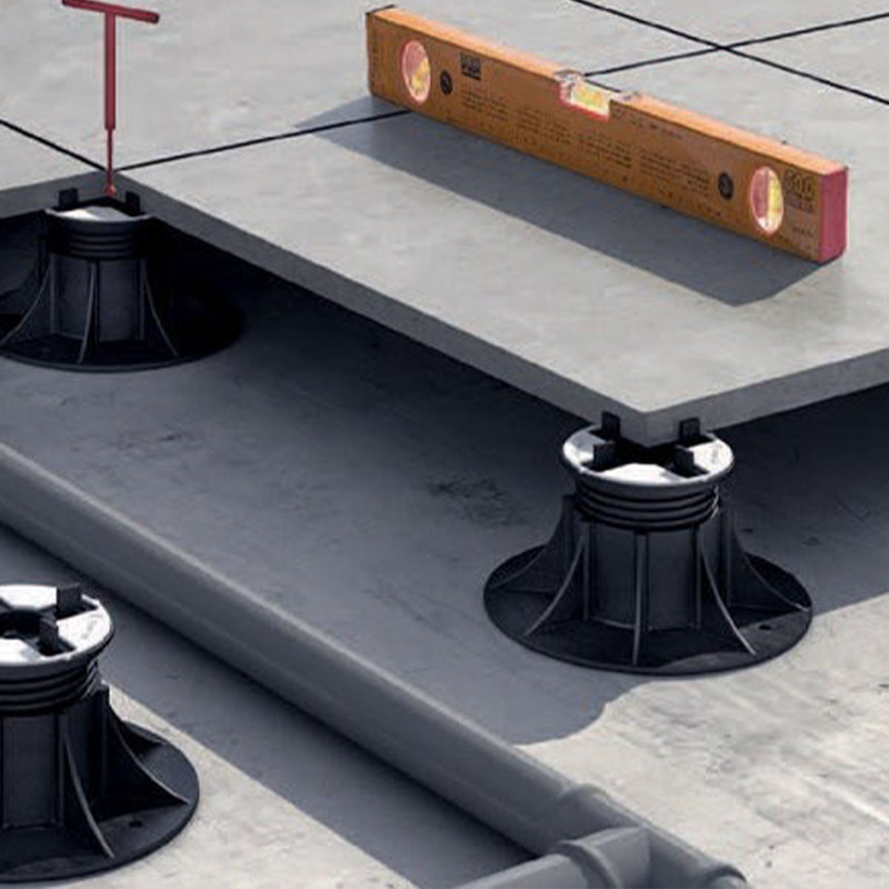 This image captures a simple yet intriguing scene that includes a level tool placed on a concrete floor. The tool is primarily black, contrasting sharply against the lighter tones of the floor. The setting seems to be outdoors, indicated by the high amount of natural light that falls onto the scene. 

The concrete floor, which makes up a significant portion of the image, has a rough texture that contributes to the rugged feel of the photograph. It's a neutral grey, offering a stark contrast to the black level. The tool itself is designed with a sleek finish, signifying its importance and functionality. 

While there are no visible people or objects in the scene, the presence of the level suggests that some sort of construction or repair work might be in progress. 