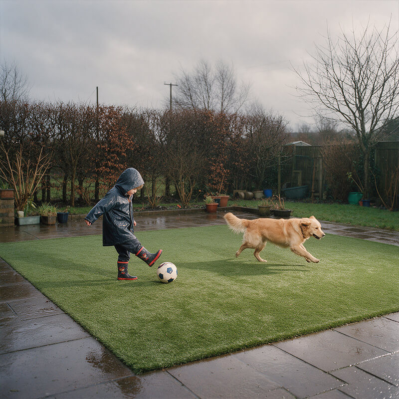 Artificial grass for kids and dogs in Ireland Child playing football with a dog on artificial grass in an Irish garden on a grey winter day