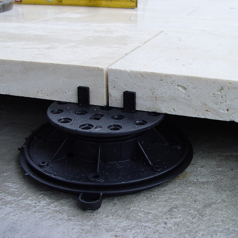 I am looking at an image that prominently features a black object, resting on a stark white surface. The object appears to be made of metal and has an intriguing design, with numerous small holes punctuating its surface. It's rectangular in shape and has a white border around it, which contrasts sharply with the black metal. This particular object doesn't seem to be indoors. The image suggests an outdoor setting, possibly evidenced by the natural lighting and the texture of the white surface. It could be a tile or even a layer of snow, given its pure white color and close-up view. There's an interesting element of gas presence, possibly indicated by the object's perforated design. It's not a vehicle, but the suggestion of transportation is oddly present. One might even mistake this object for a tray, due to its rectangular form and flat surface. Finally, in terms of color composition, the image predominantly features shades of grey, white, and black. A subtle hint of yellow presents itself, adding a warm touch to this otherwise monochrome scene. No human faces, landmarks, or recognizable text are present in this image. It's a simple yet fascinating composition, with the black object as the undisputed focal point.