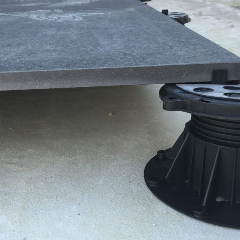 The pedestal system for tiles on the floor ensures a sturdy foundation for the black trash can on the cement sidewalk.
