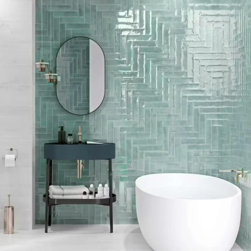 Green gloss ceramic wall tiles Bathroom with green gloss ceramic wall tiles in a herringbone pattern, a freestanding bath and a black washstand