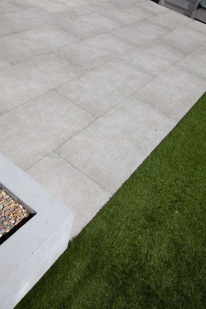 The nice contrast between outdoor porcelain tiles and artificial grass makes every garden look beautiful